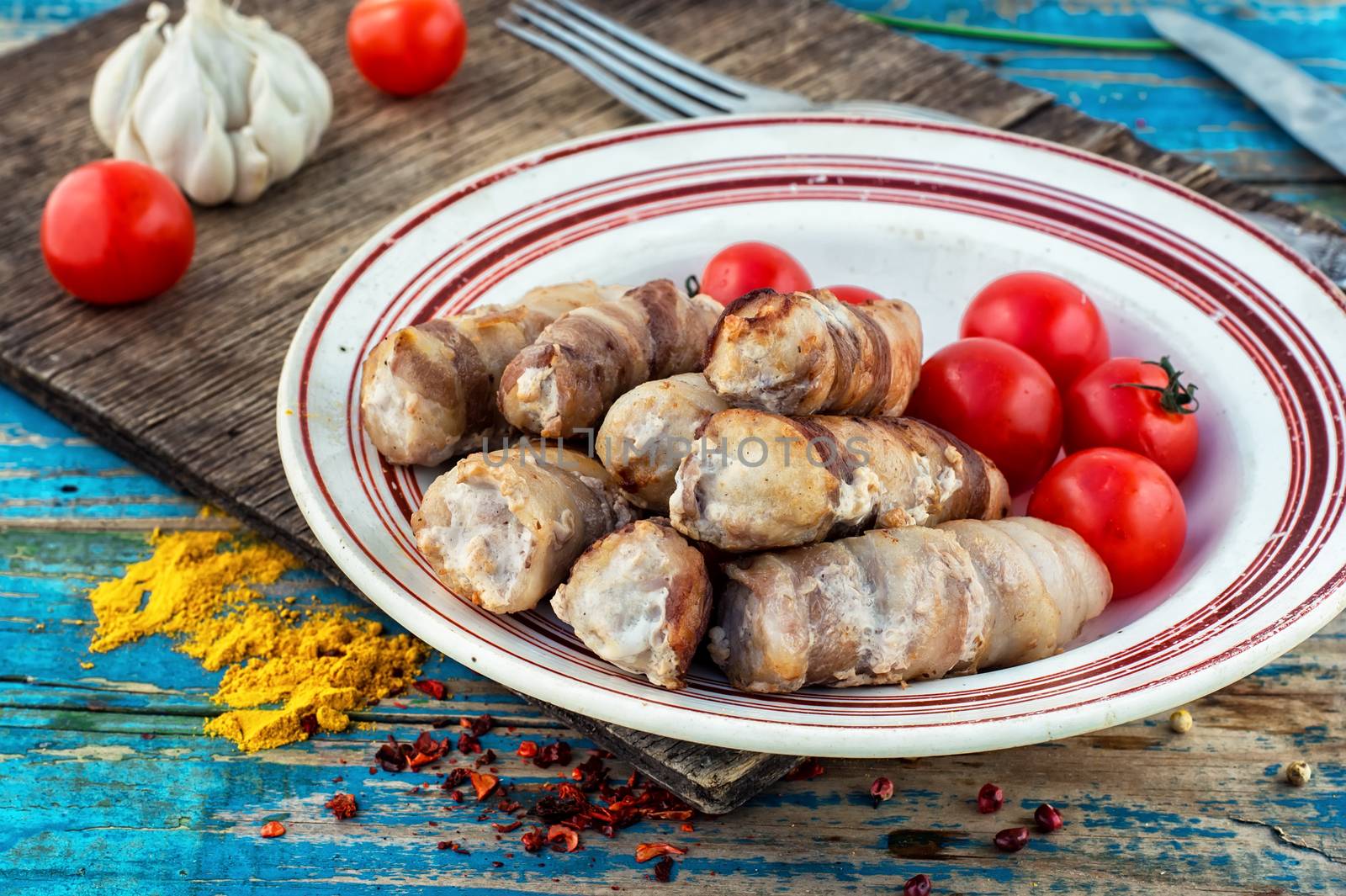 Turkey sausages roasted on round plate on wooden surface with tomatoes and spices.The image is tinted.Selective focus