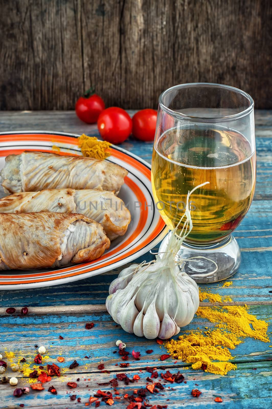 Turkey sausages roasted on a round plate on a wooden surface with glass of light beer.The image is tinted.Selective focus
