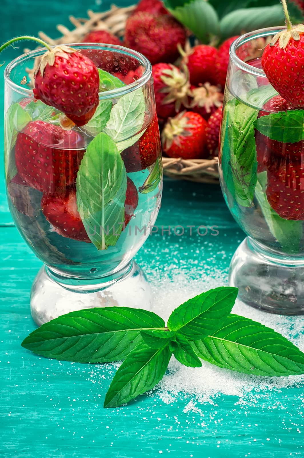 glass with drink of strawberries and mint on the background of the basket full berries.Selective focus.Photo tinted
