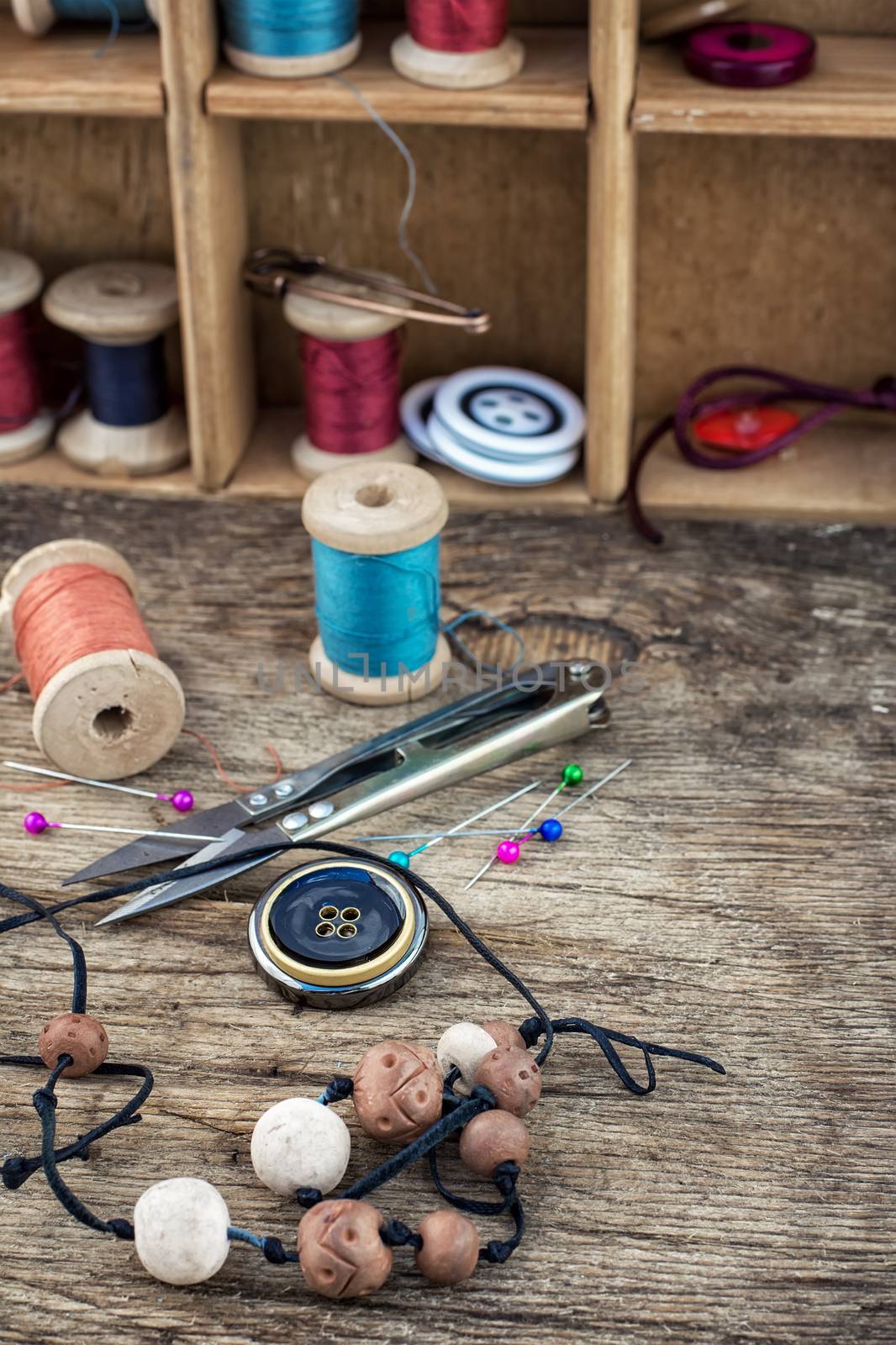 beads,thread,buttons craftswomen on wooden background.Selective focus.Photo tinted