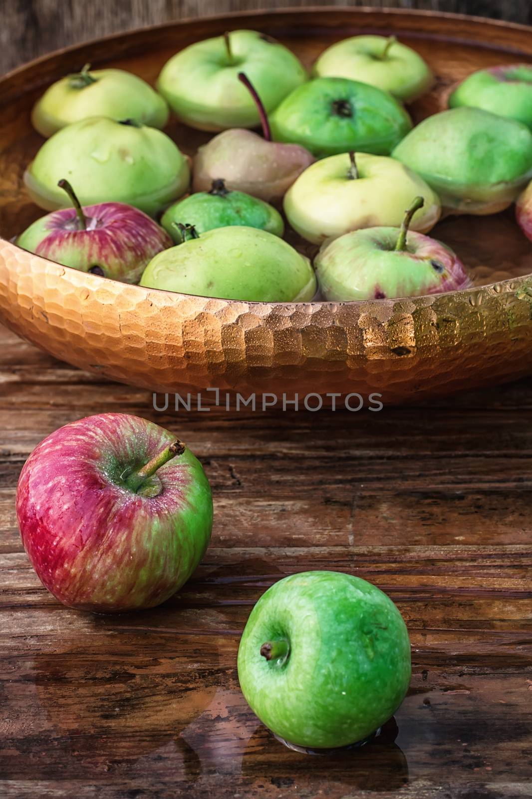 Autumn harvest of apples in the bowl of water on wooden background.Photo tinted.