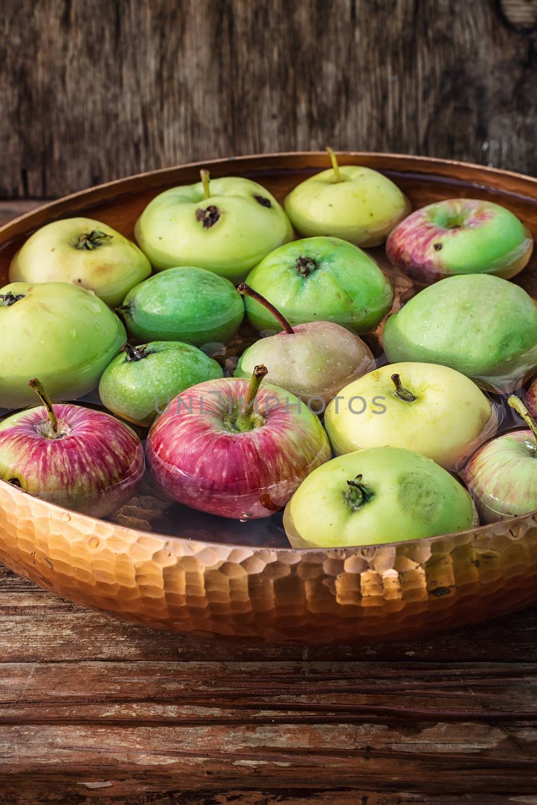 Autumn harvest of apples in the bowl of water on wooden background.Photo tinted.