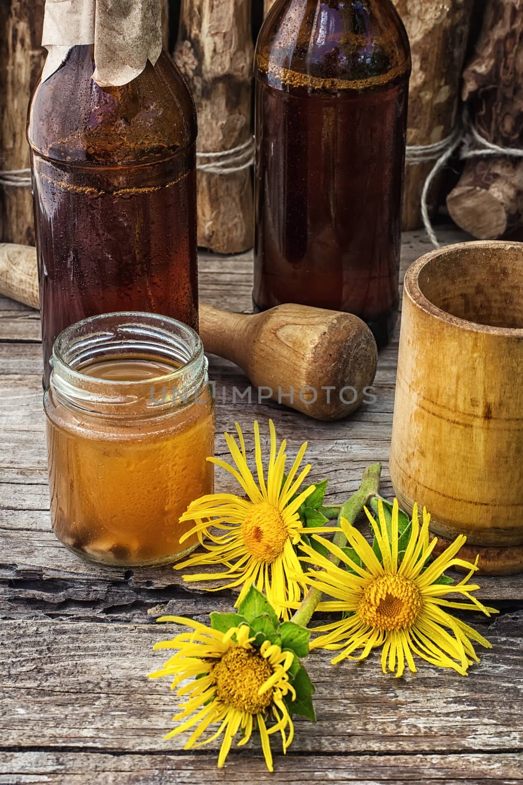 infusion of inflorescences and roots of the medicinal plant Inula on the wooden table next mortar and pestle.Photo tinted.Selective focus