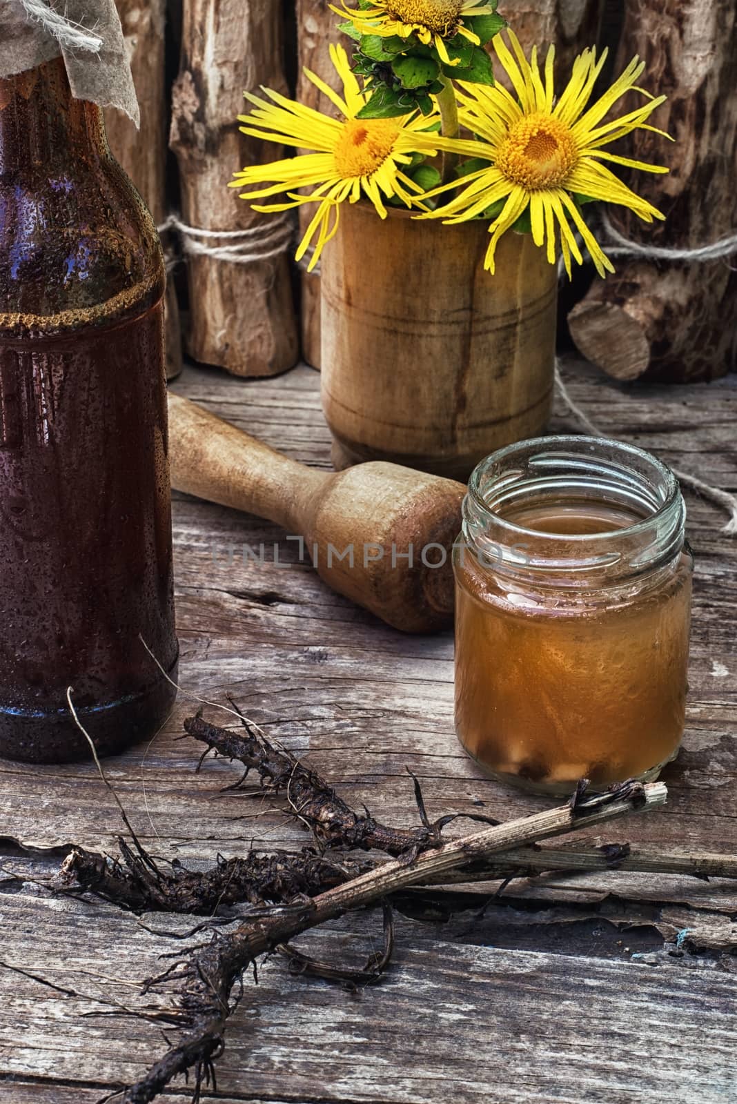 infusion of inflorescences and roots of the medicinal plant Inula on the wooden table next mortar and pestle.Photo tinted.