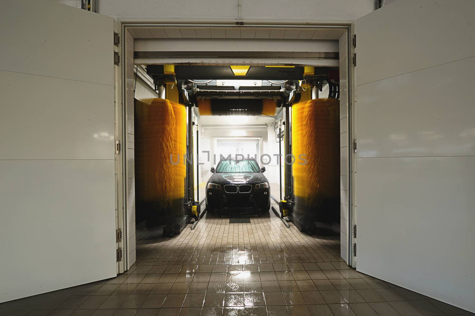 station washing tunnel with white gate and car in it