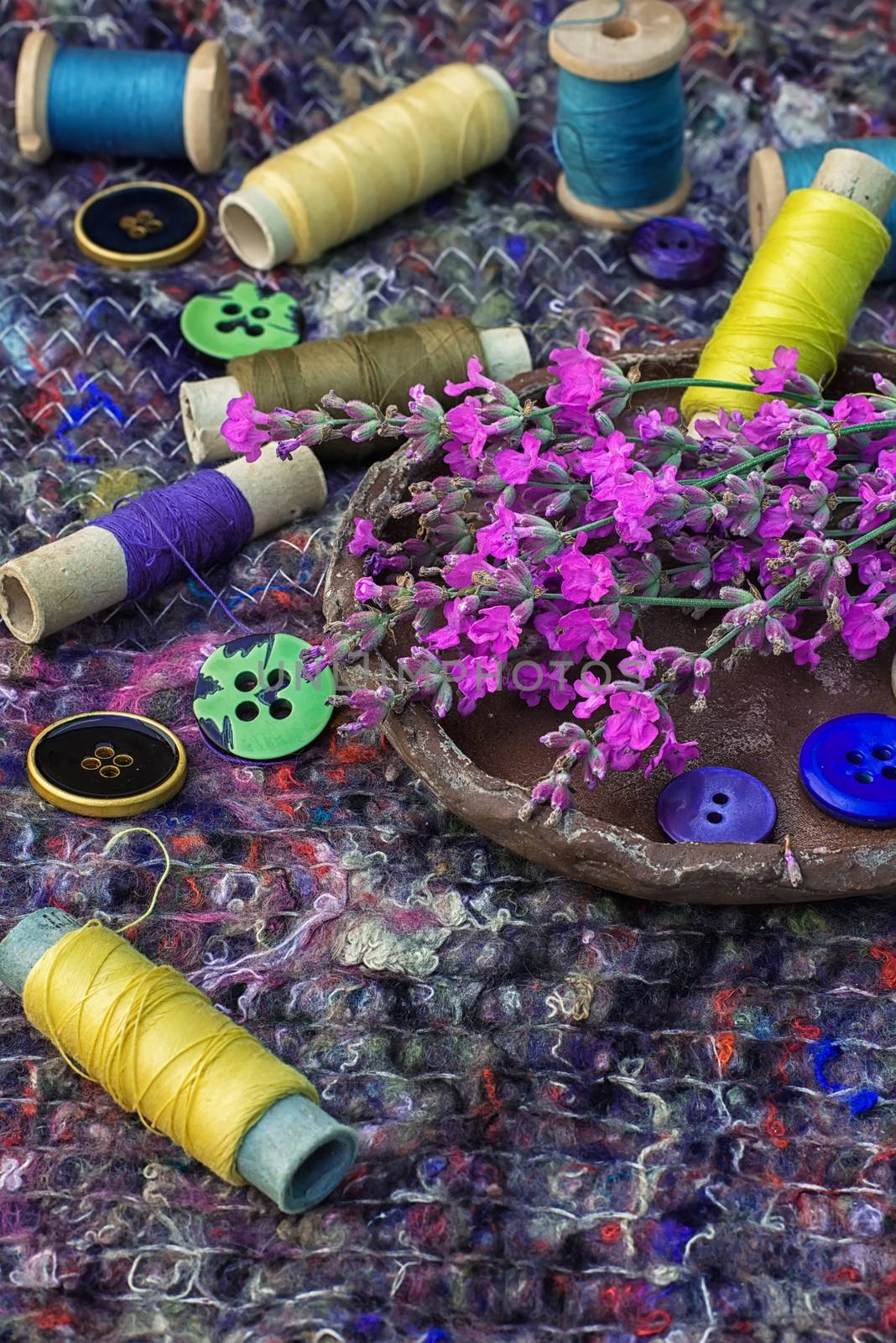 sewing thread and buttons on the background batting is decorated with blooming lavender.Photo tinted.Selective focus