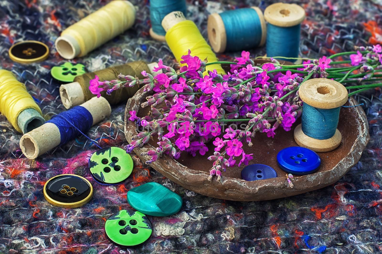 sewing thread and buttons on the background batting is decorated with blooming lavender.Photo tinted.