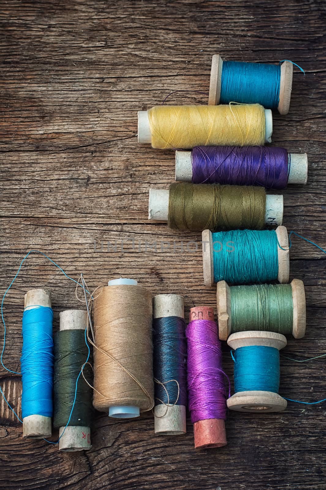 spools of thread on the old wooden background.Photo tinted