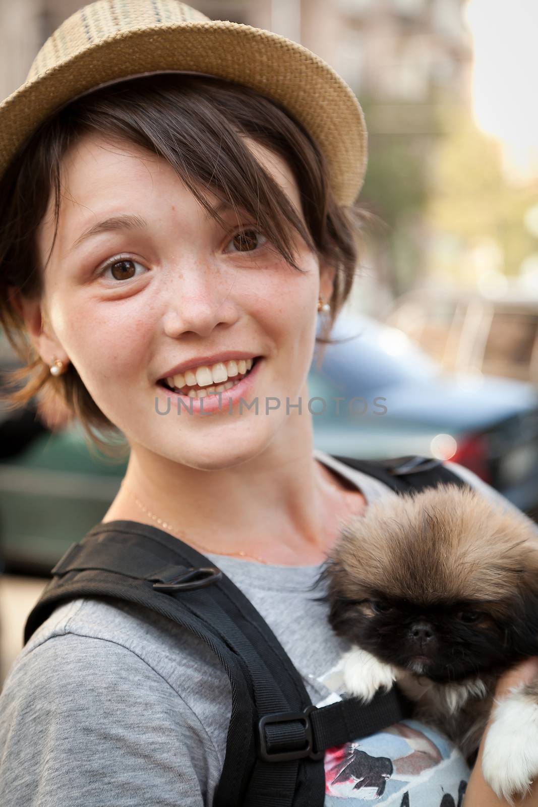 the young beautiful woman in a hat holds a little puppy in hand
