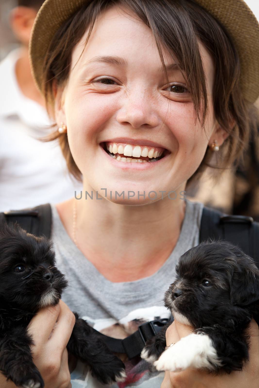 the young beautiful woman in a hat holds two little puppies in hand