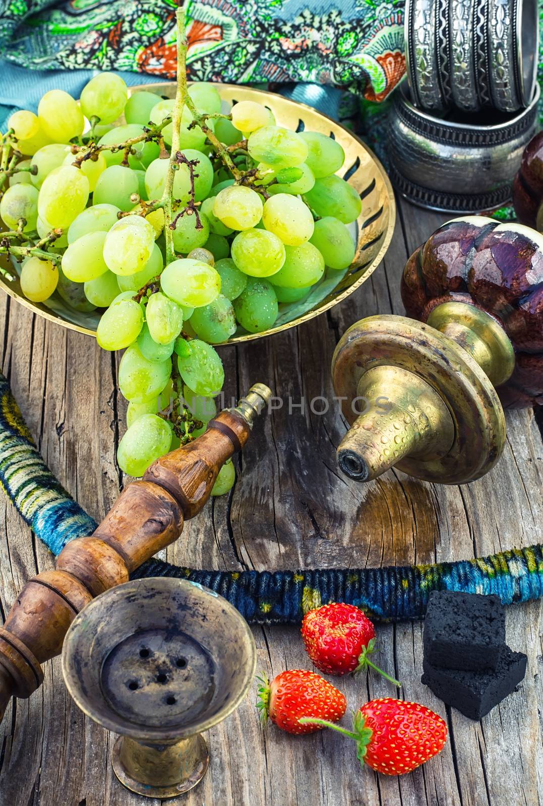 details vintage smoking hookah on wooden table on background of ripe grapes and strawberries