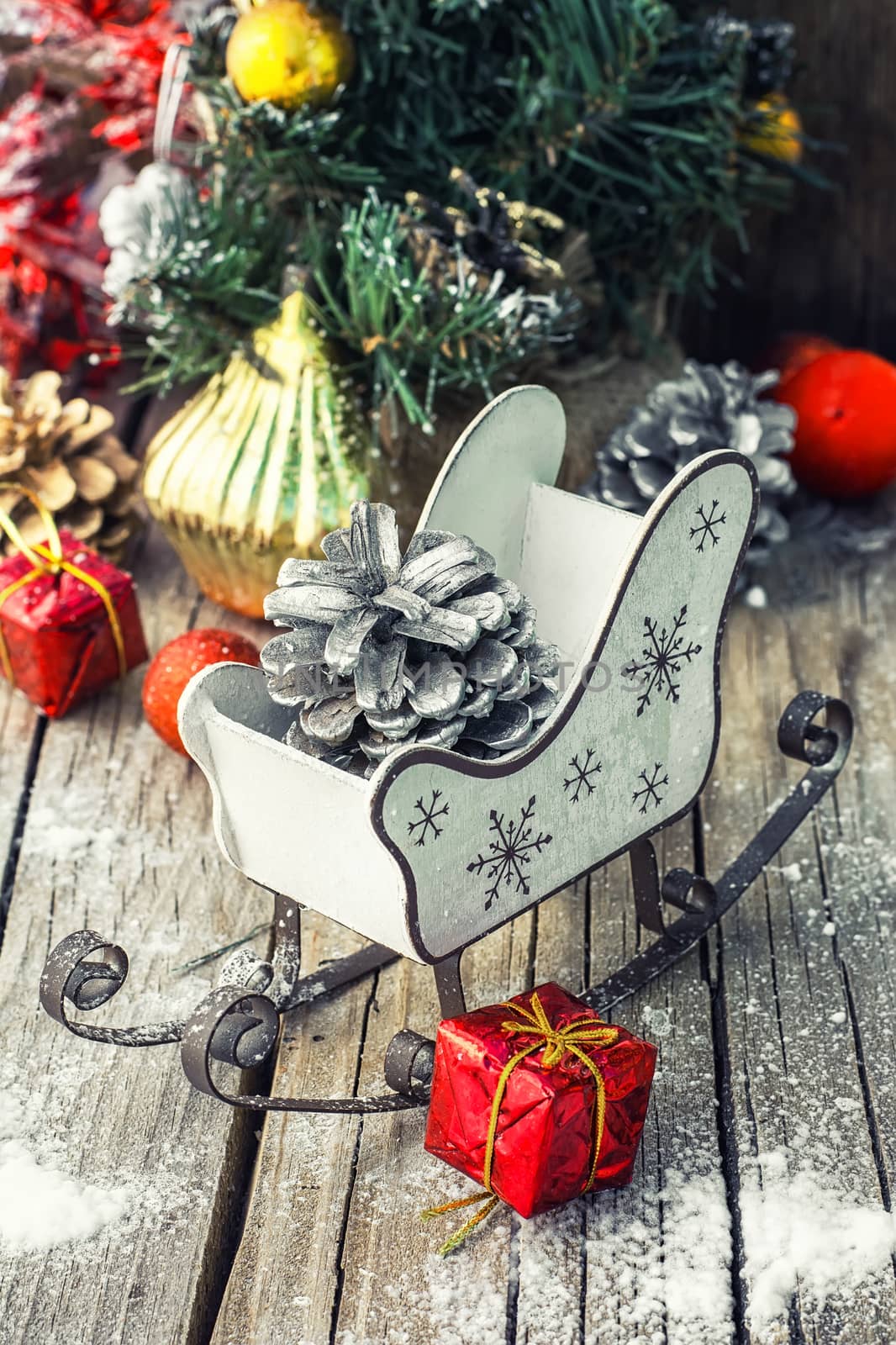 Christmas sleigh with pine cones and decorations on wooden background.