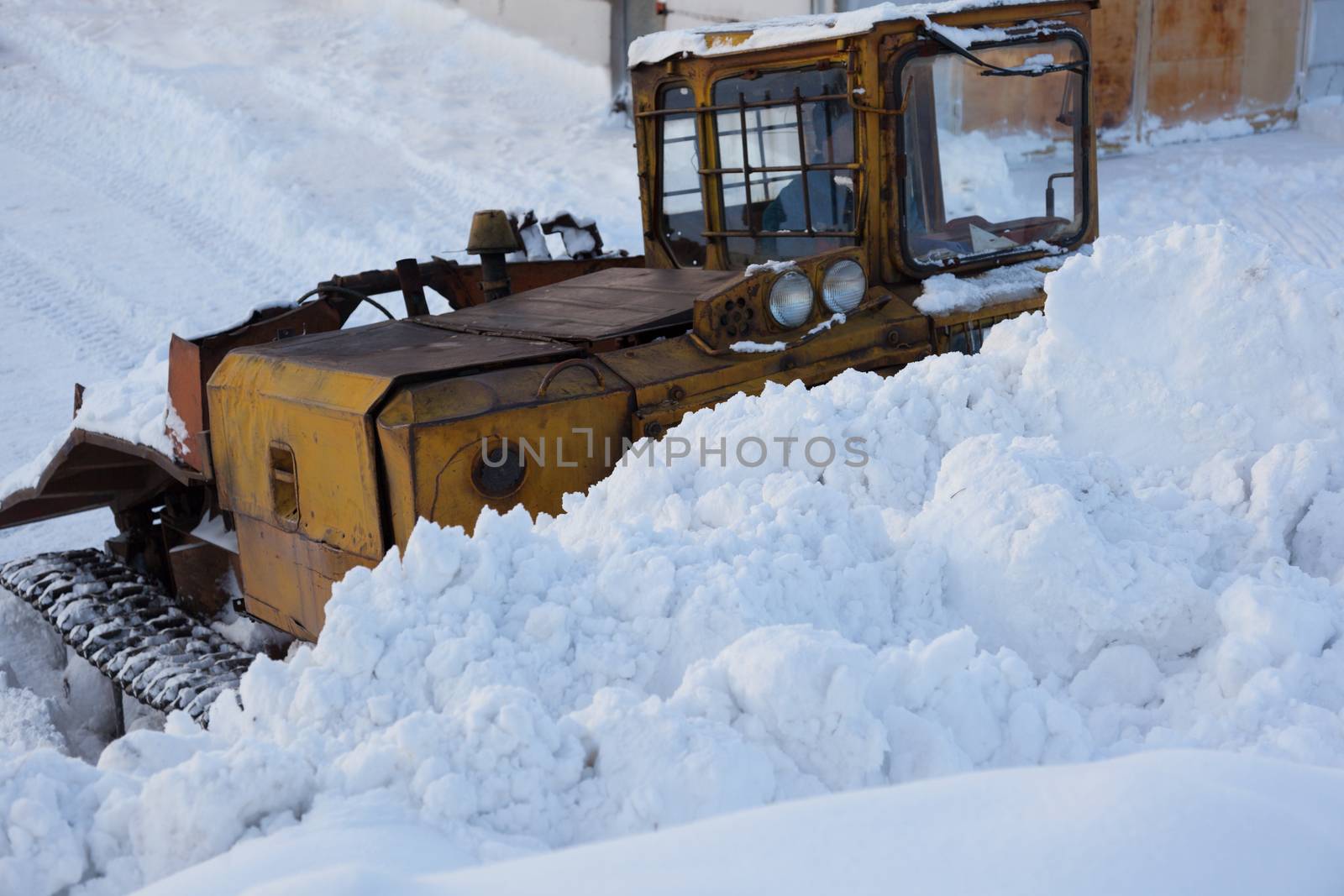 Snow removal in the winter. Tractor with scraper in winter day. The snow-removing machines