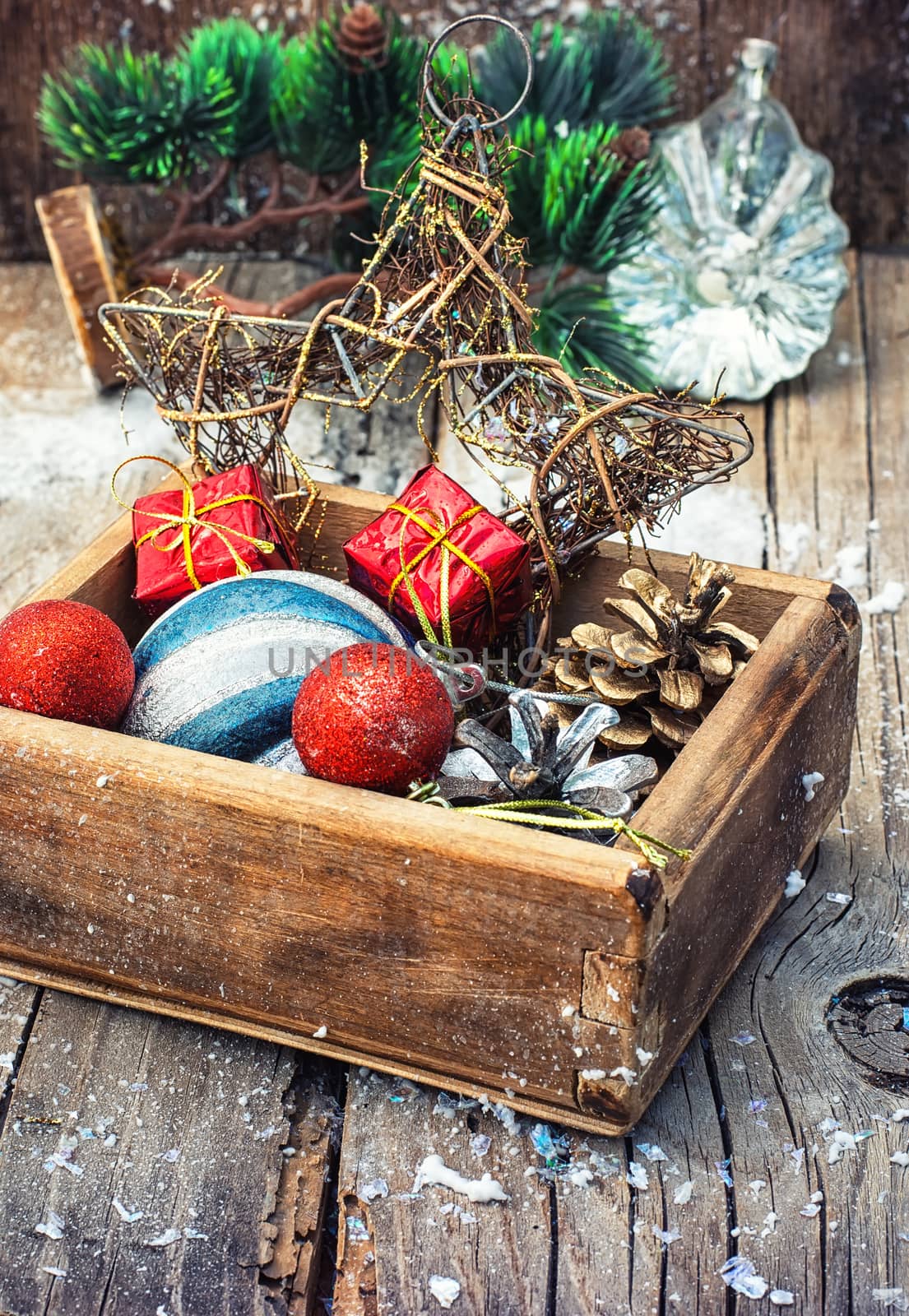 Wooden box full of Christmas toys and cones on wooden background.Selective focus