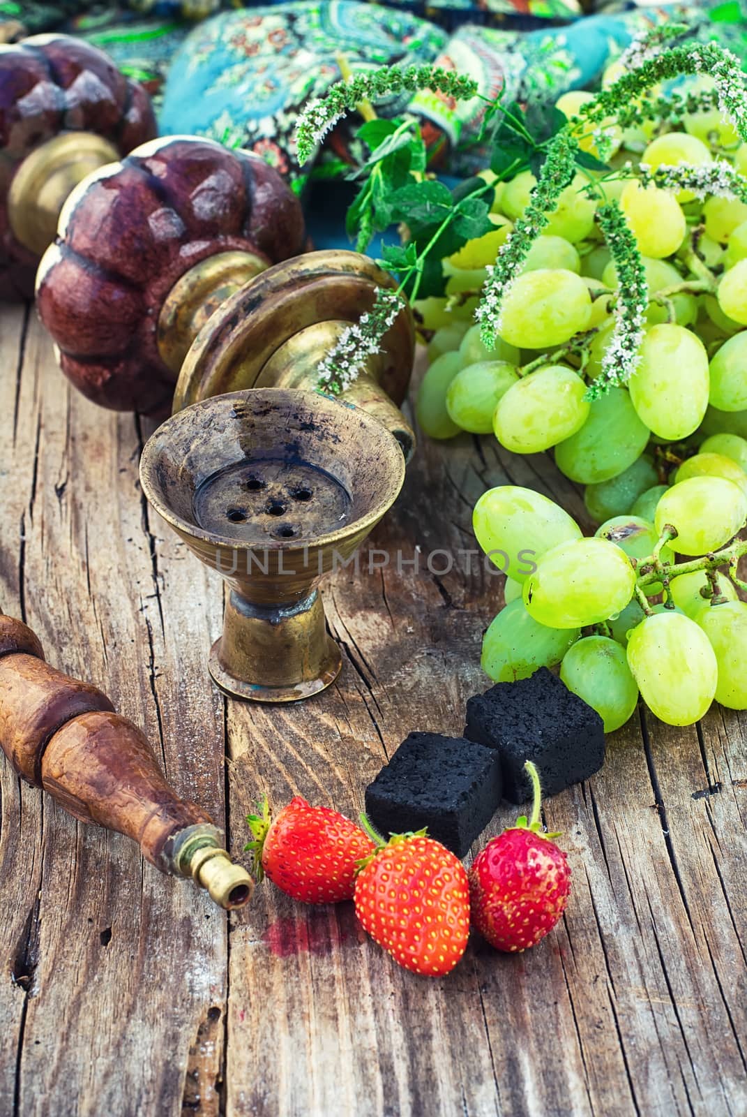Old smoking  hookah and bunch of grapes on wooden surface.