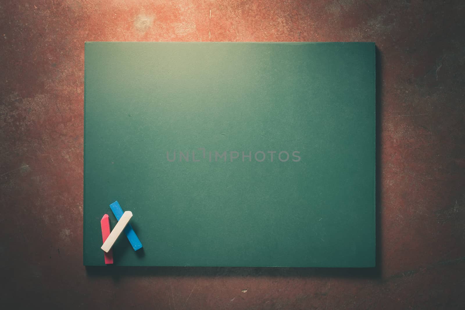 Small black board in green color with blank space for text or message on veteran red cement background with low key scene and vintage filter effect