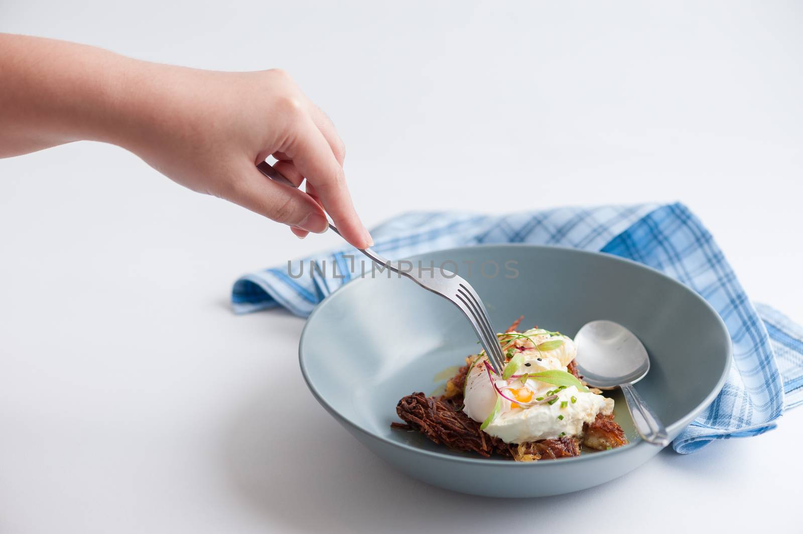 Woman left hand with fork stab on hash brown with Halloumi cheese and savory dressing
