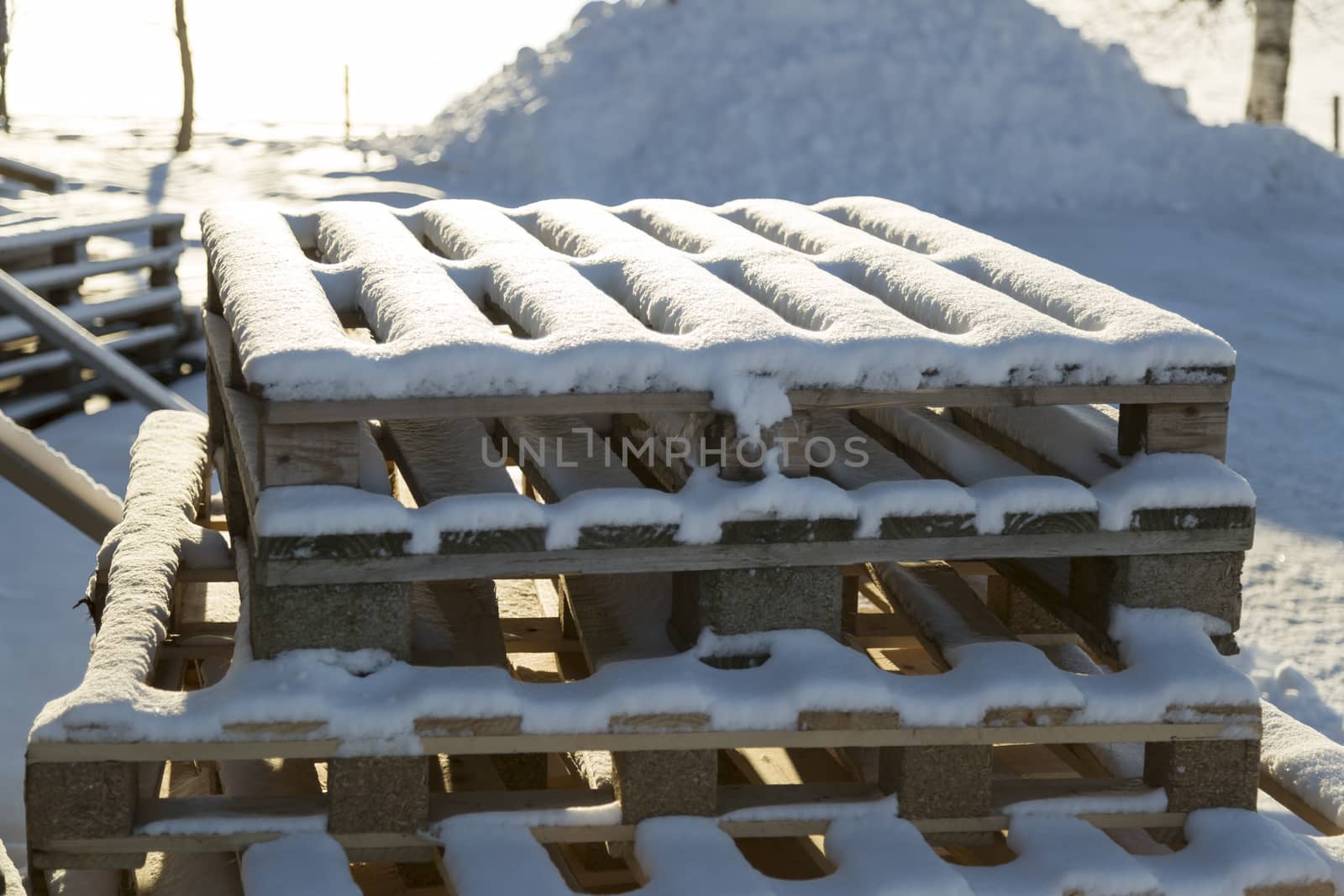 Box Pallets Covered in Snow stacked on top of each other.