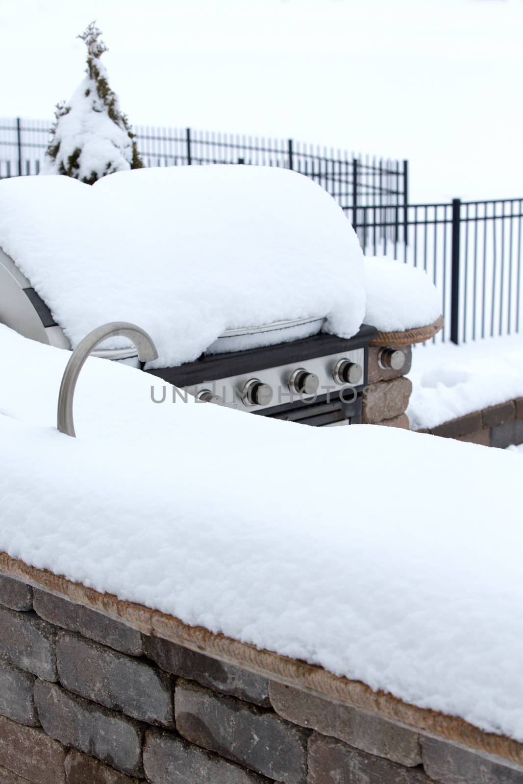 Detail of BBQ on Stone Patio Buried Beneath Heavy Snow in Winter - Disused Outdoor Kitchen Neglected Under Winter Snow in Back Yard of Home