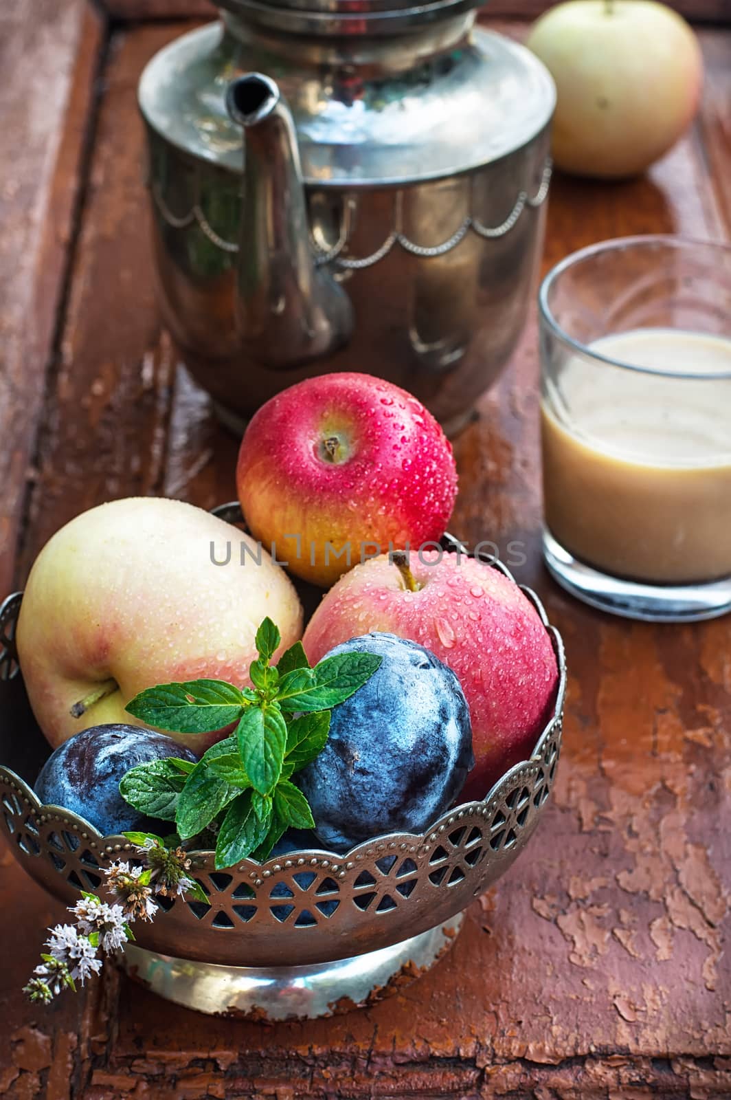 apples and plums in iron vase, teapot and cup of coffee