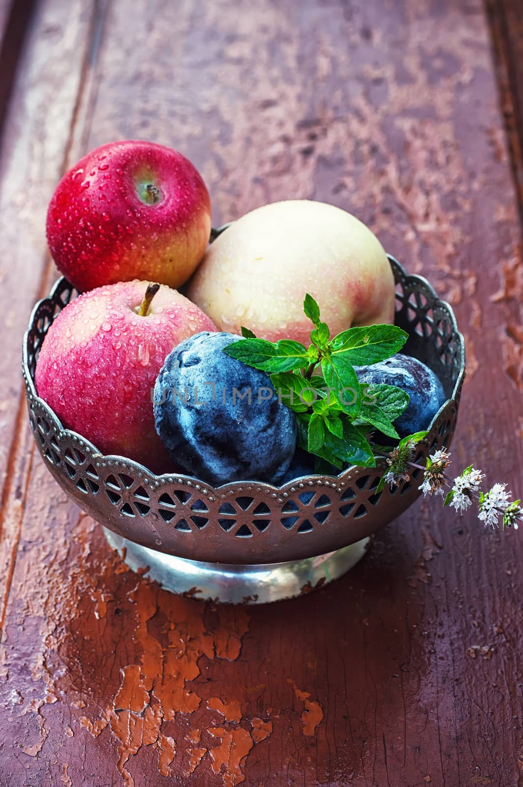 apples and plums in iron vase on strensham wooden background