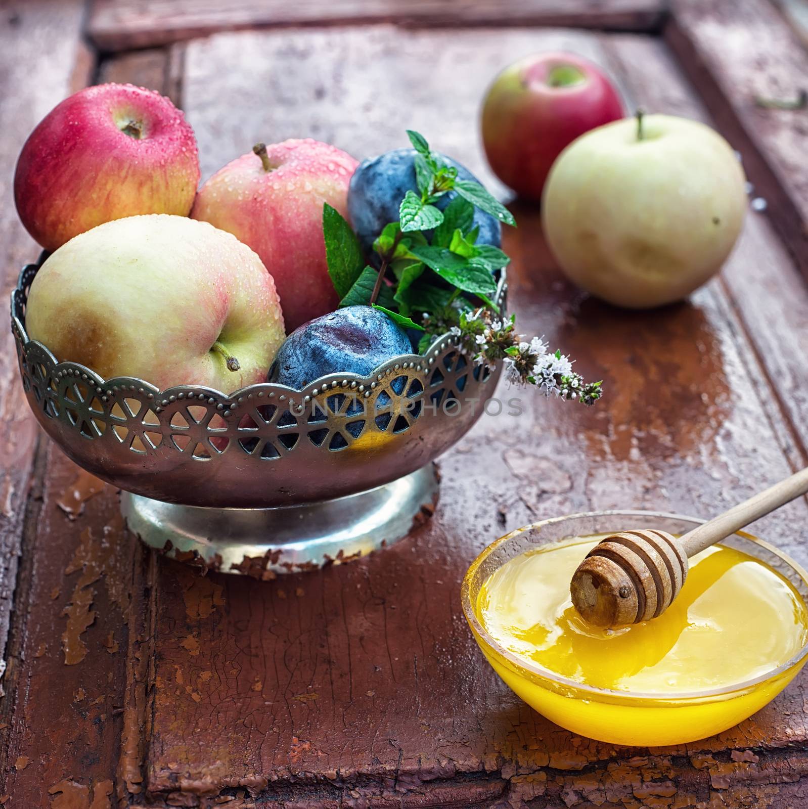 apples and plums in iron vase and saucer with fresh honey