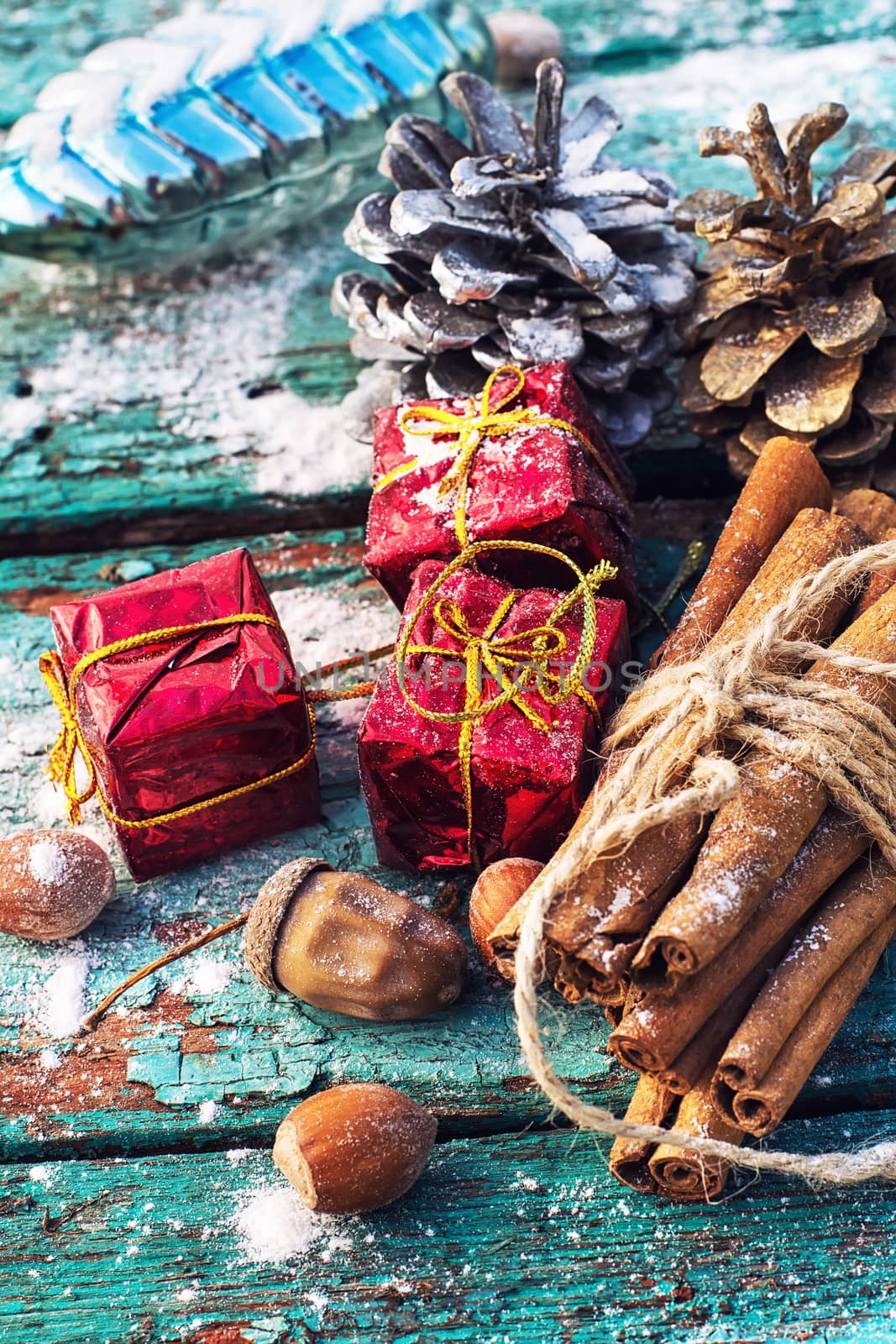 Gifts and decorations for Christmas on wooden background strewn with pine cones and spices