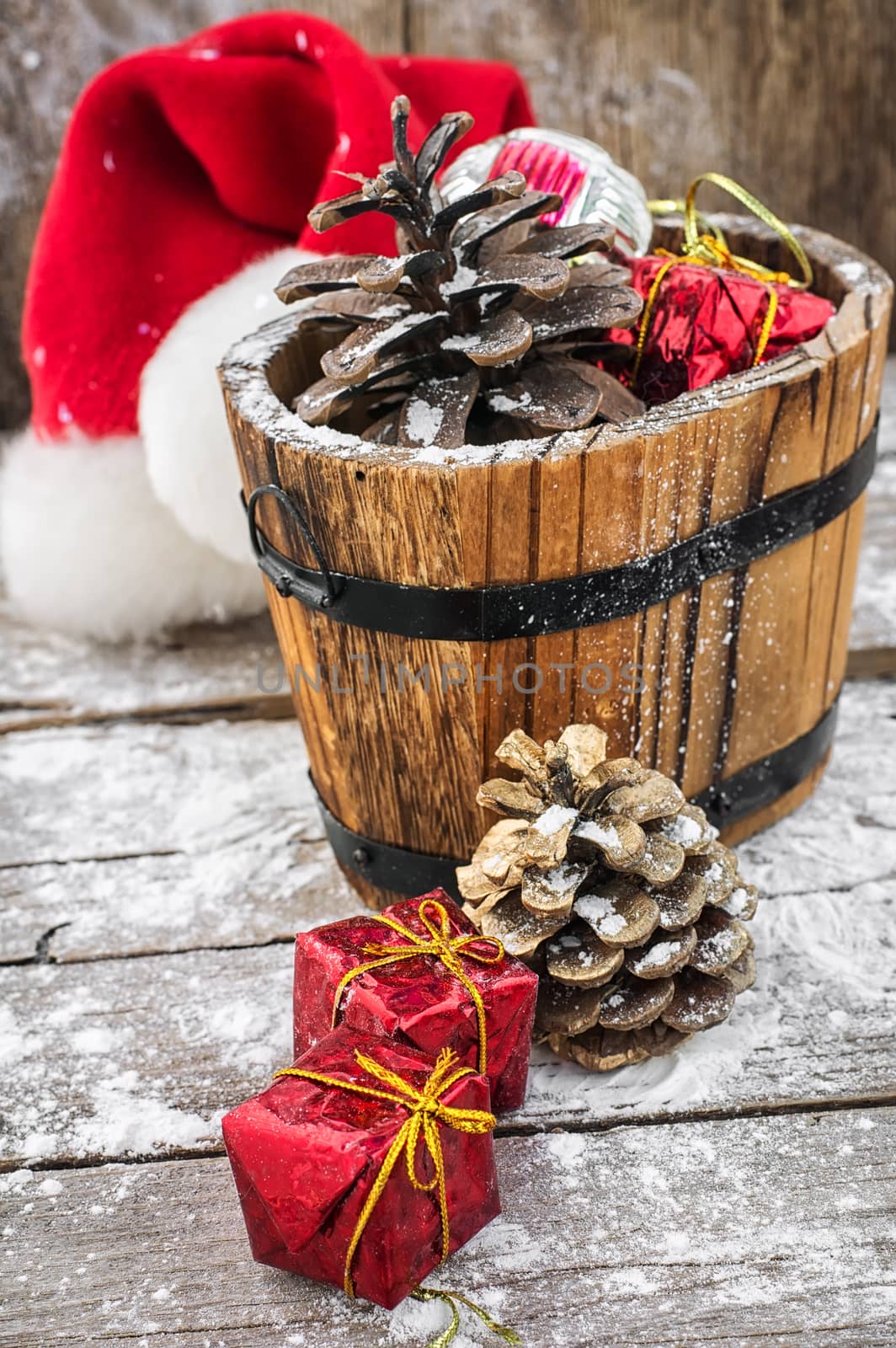 wooden tub filled with pine cones and Christmas ornaments on  background of snow