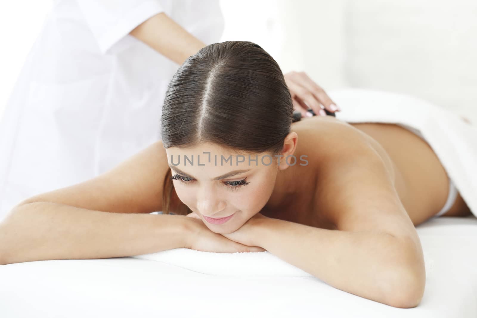 Young beautiful woman in spa getting hot stone massage