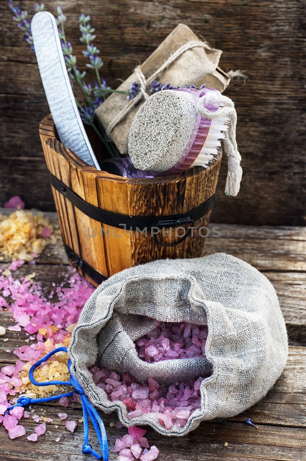 Scrub,brush,nail file in wooden tub on the background scattered with sea salt for Spa treatments.