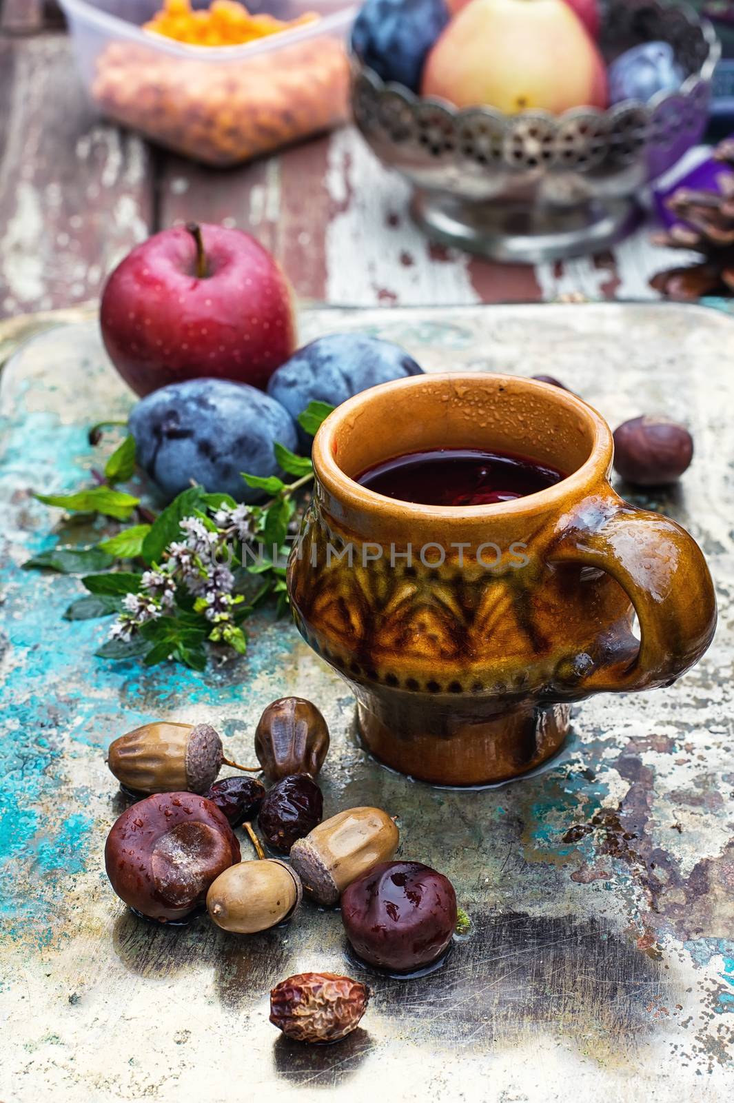 mug with herbal tea on  background of apples and plums in the autumn garden