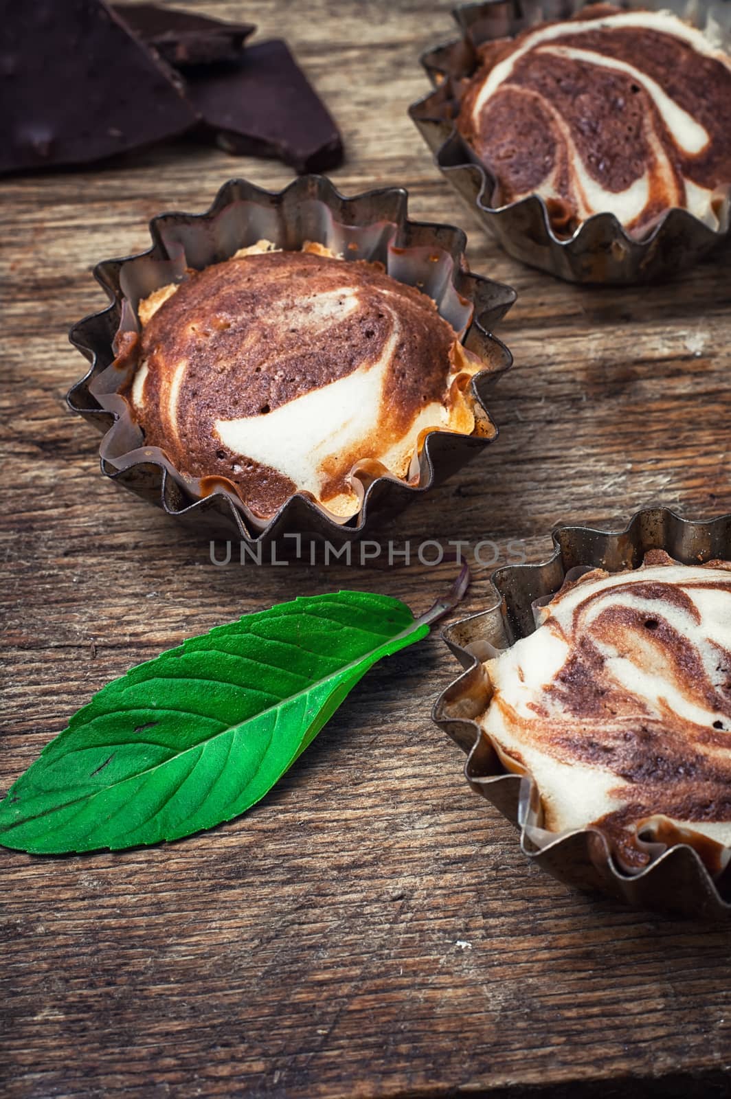 Baked chocolate cupcakes in tins on wooden table