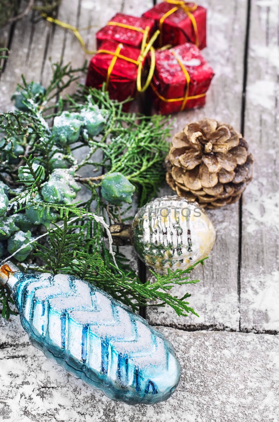 Christmas decorations under the branches of fir tree on  snowy wood plank