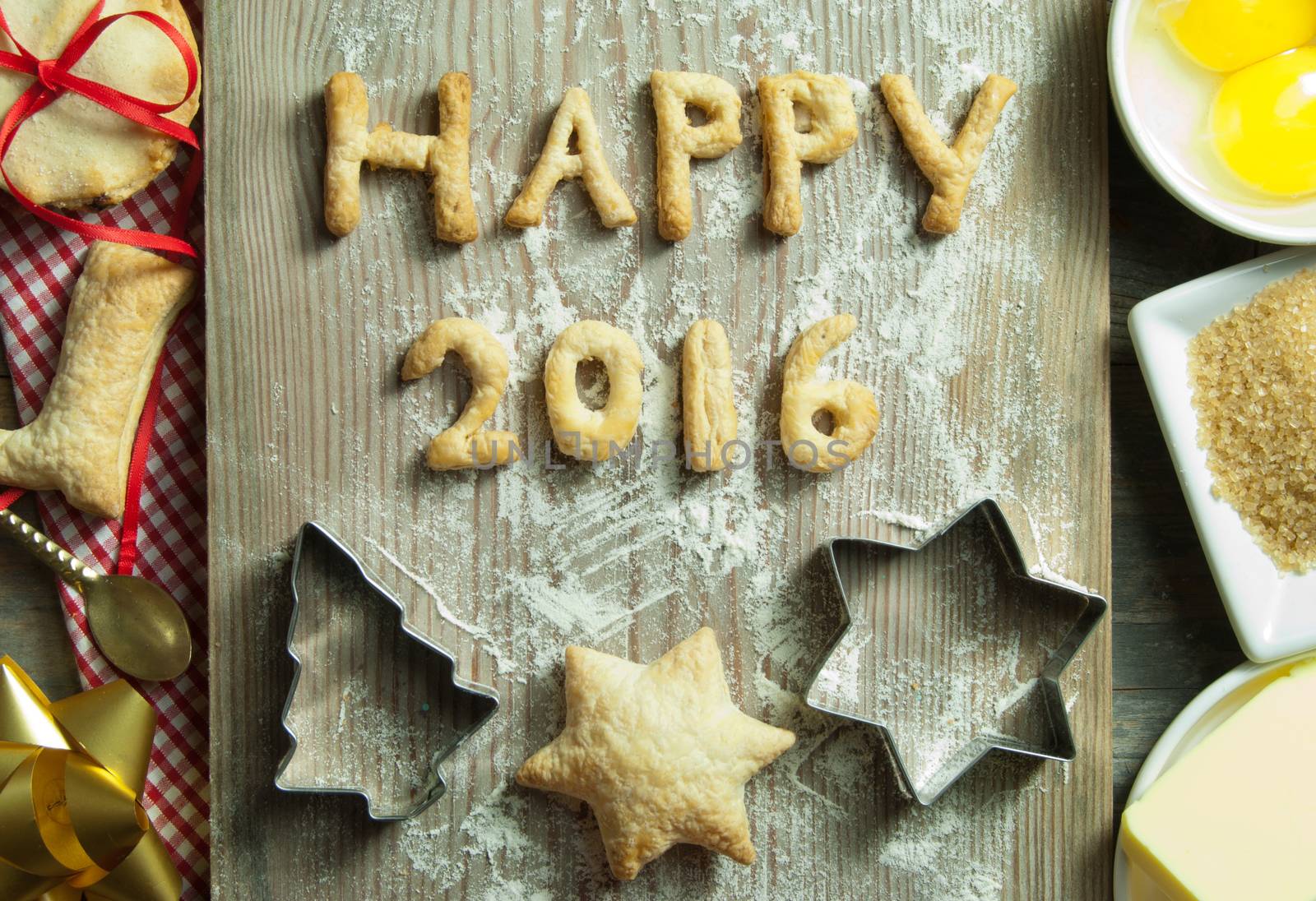 Happy 2016 made from cookies on top of a chopping board with baking ingredients