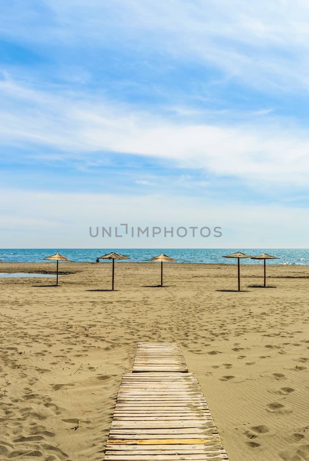 Wooden parasols on sandy seaside  by radzonimo