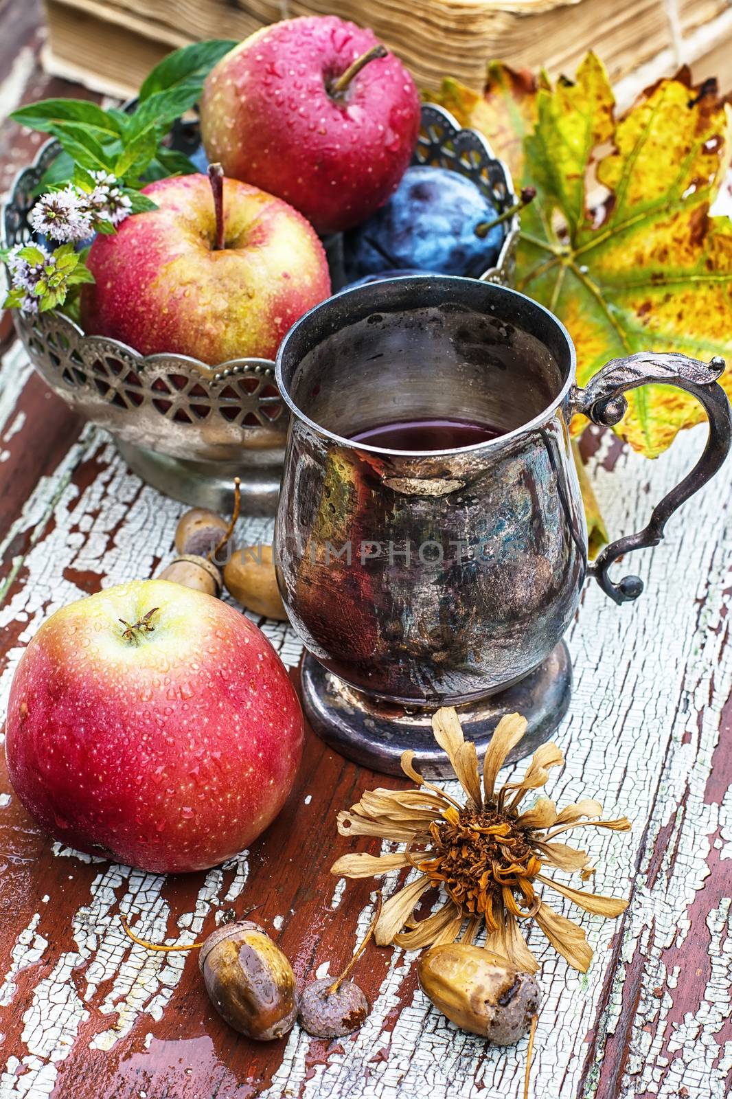 mug with herbal tea on  background of apples and plums in the autumn garden