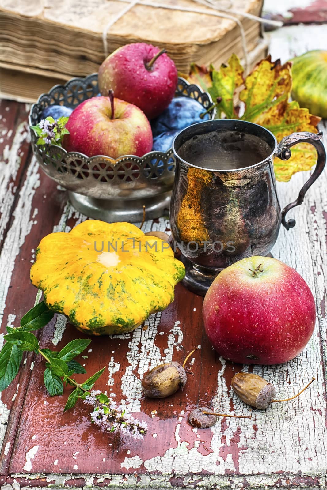 mug with herbal tea on  background of apples and plums in the autumn garden