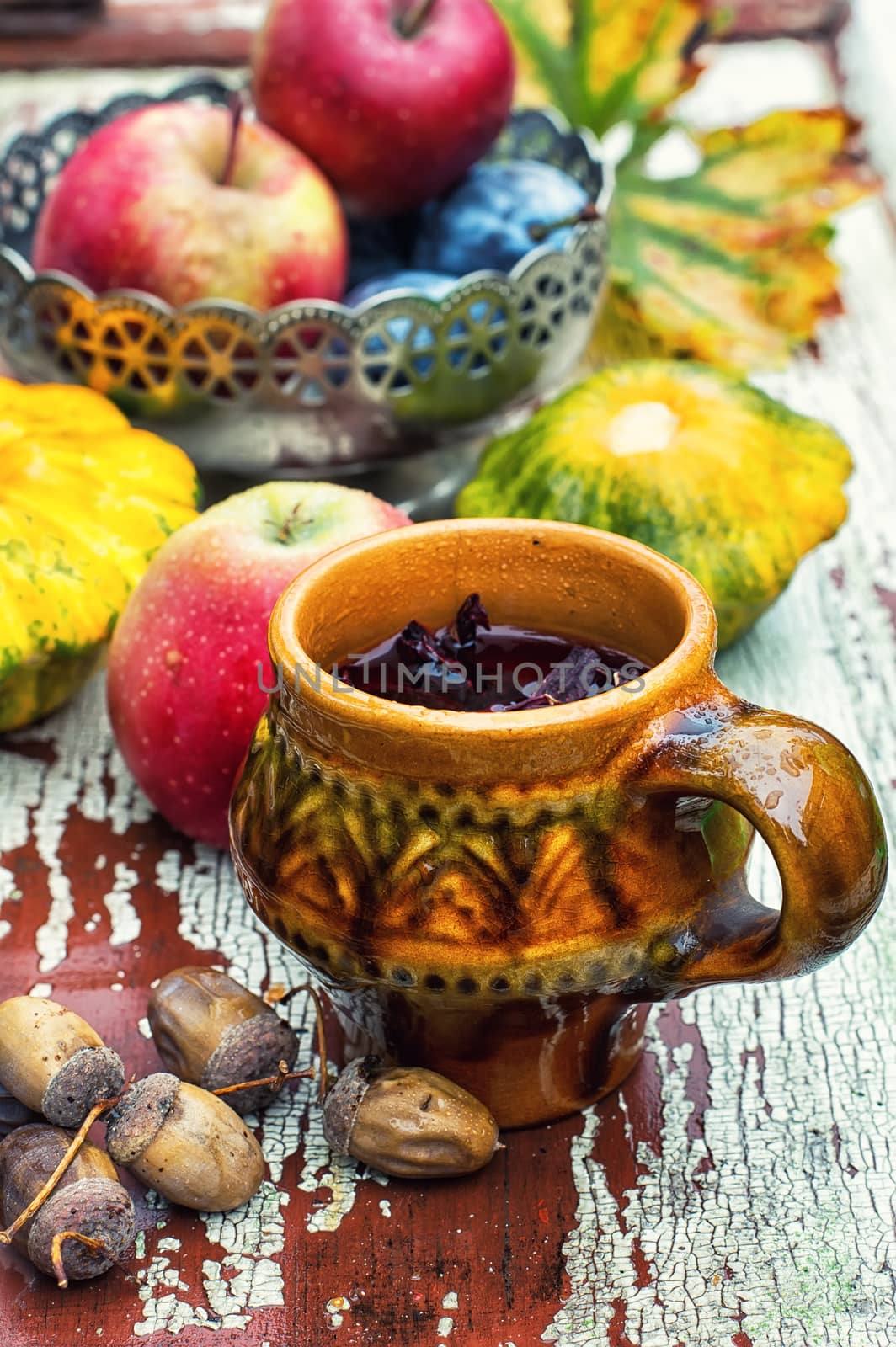 clay mug with herbal tea on  background of apples and plums in the autumn garden.Selective focus
