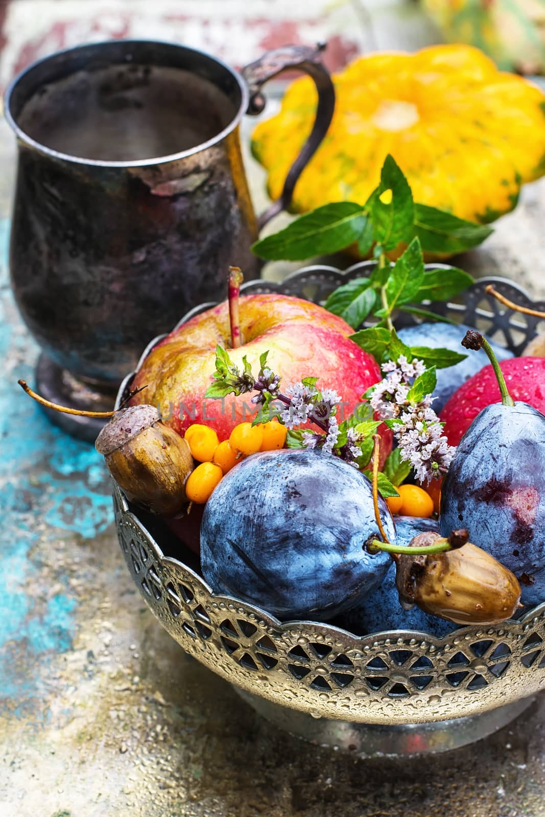 mug with herbal tea on  background of apples and plums in the autumn garden.Selective focus