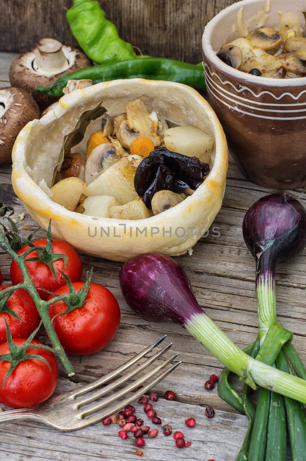 mushrooms baked with potatoes in bread pot amid onion and tomato