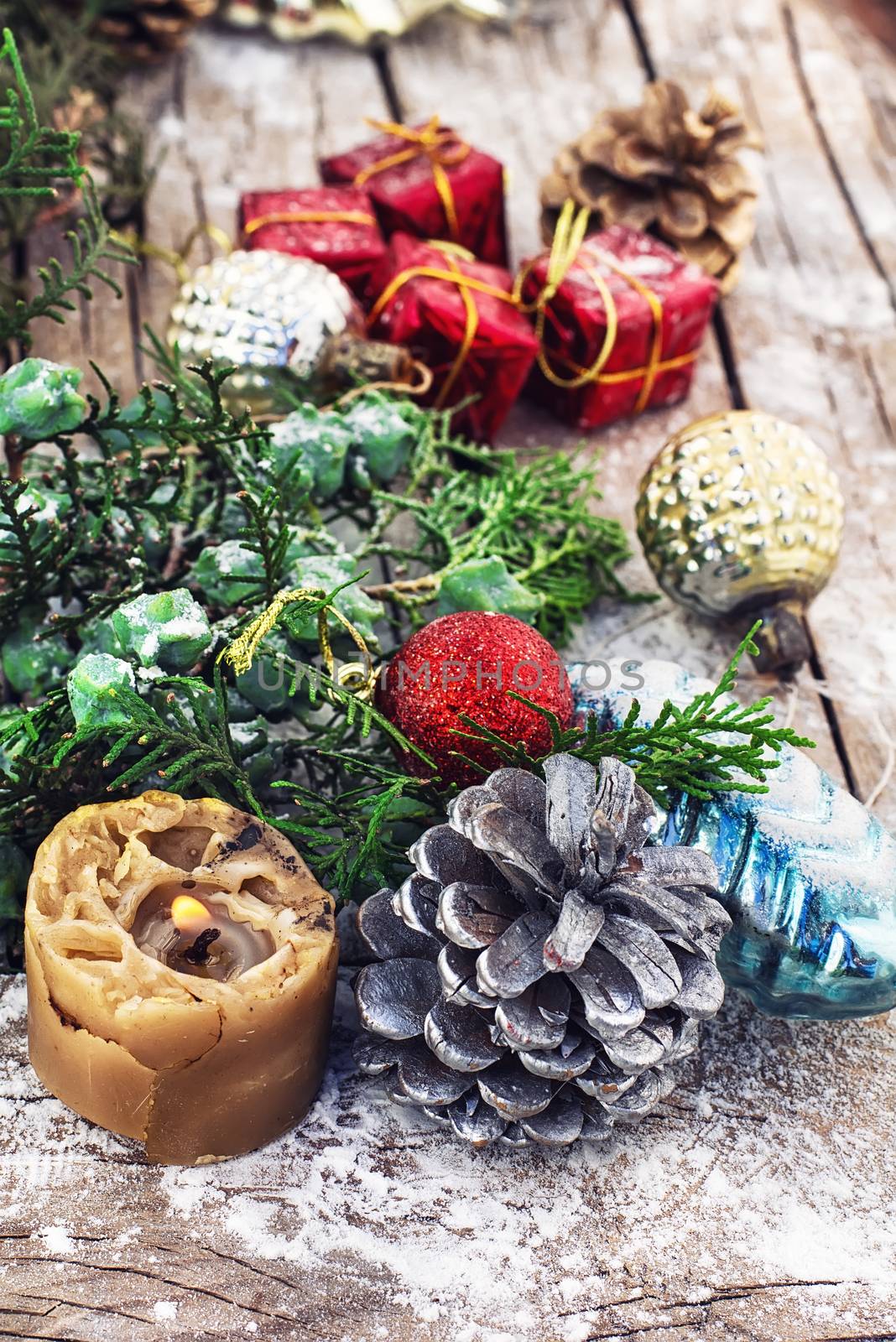 Christmas decorations under the branches of fir tree on  snowy wood plank