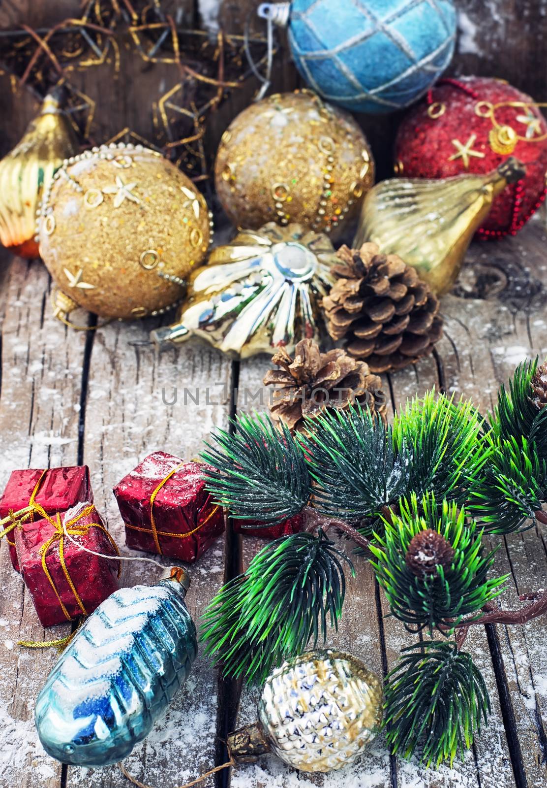 Christmas decorations under the branches of fir tree on  snowy wood plank