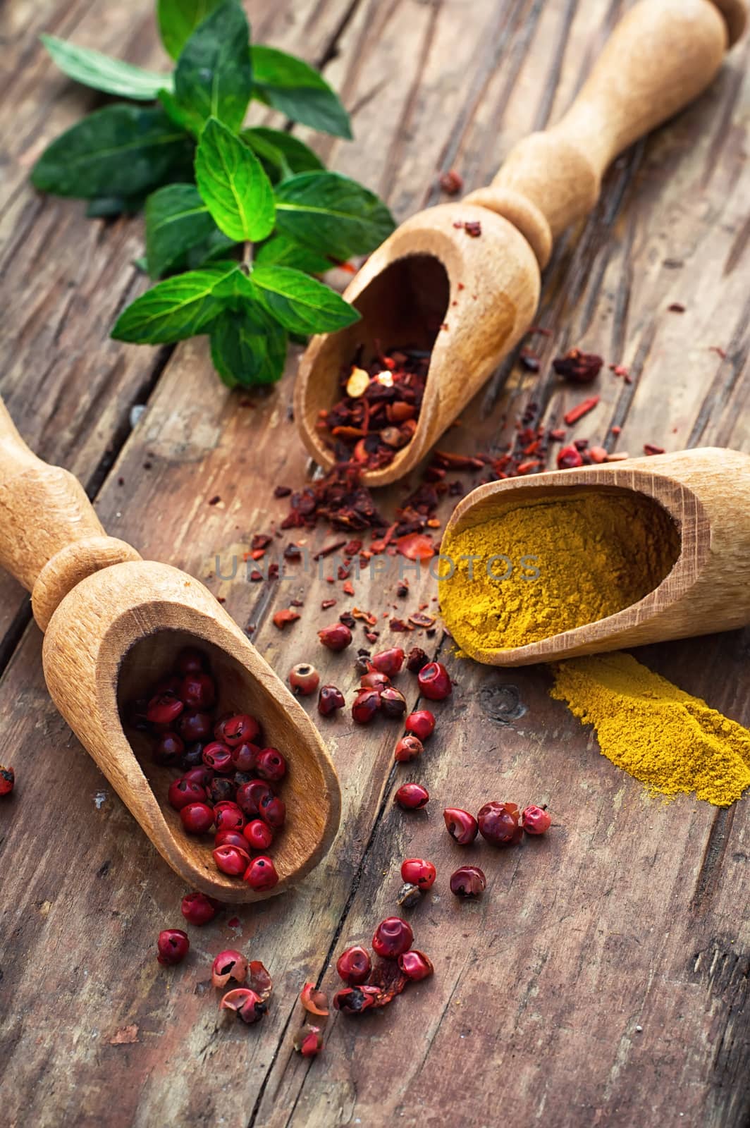 Three wooden shovel with a variety of spices on wooden background in rustic style