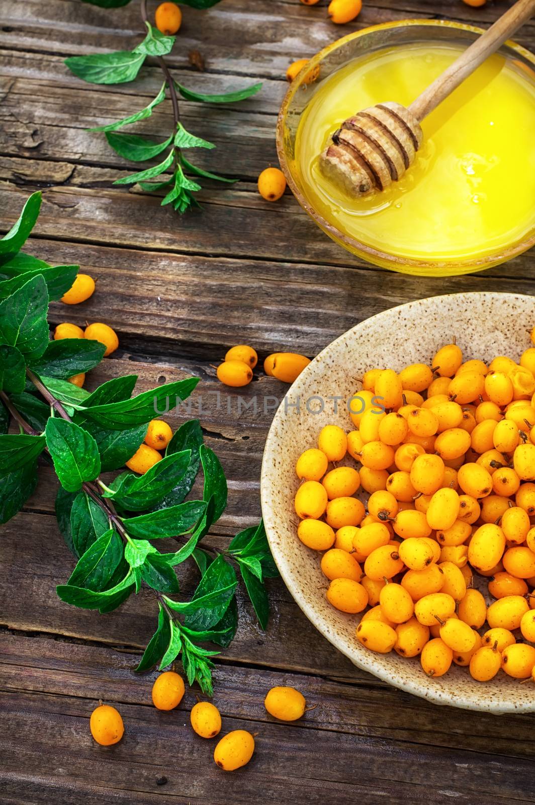 Ripe berries of sea buckthorn in  saucer on wooden background
