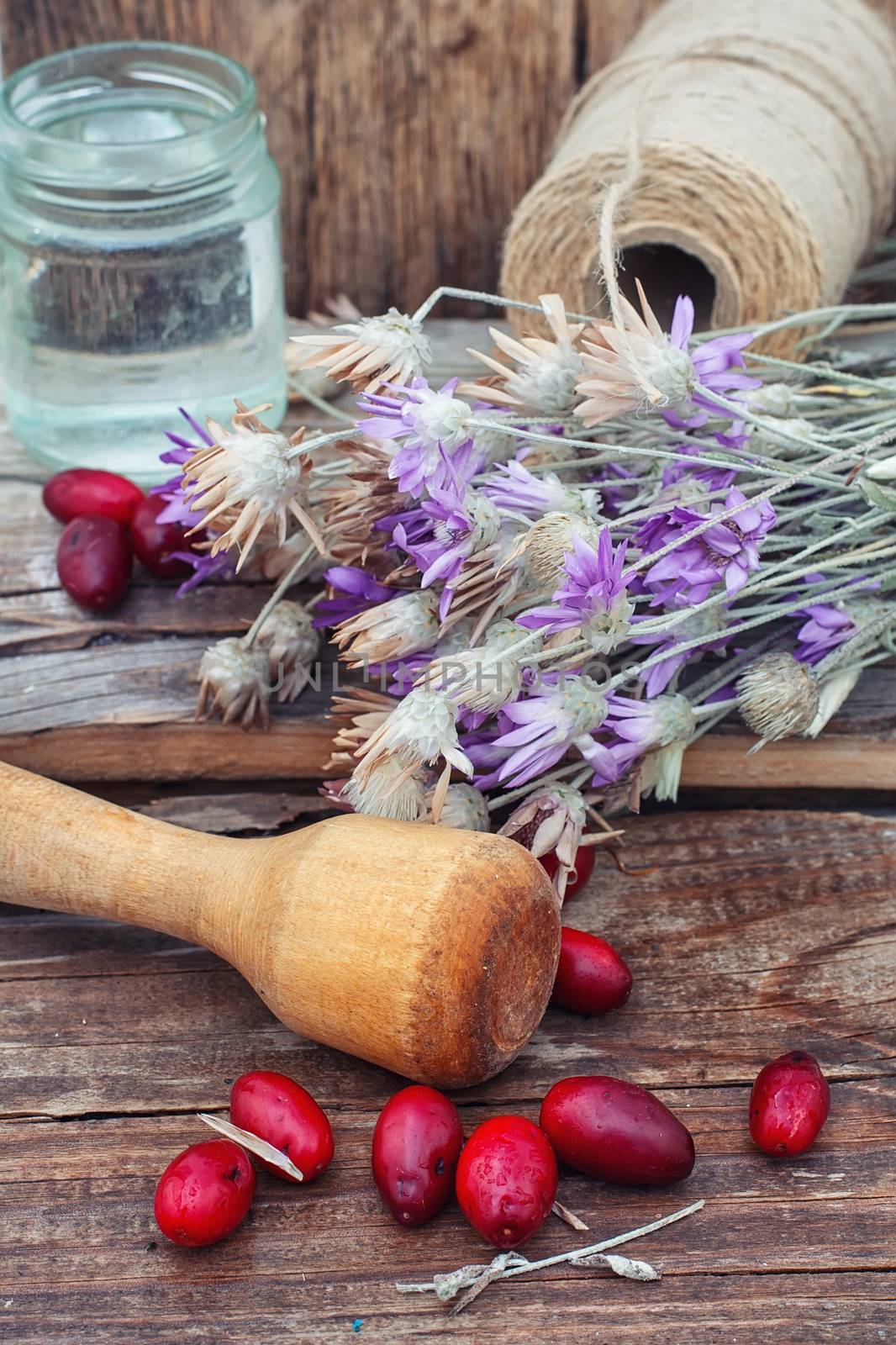 scattered medicinal Cornel berries and bowl of seeds of Heather on wooden table