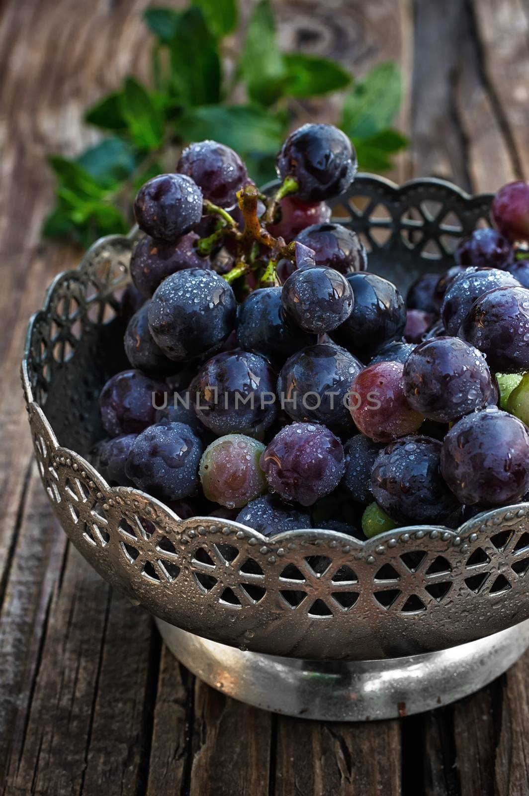 Brush ripe and juicy grapes in  vintage iron vase on wooden background
