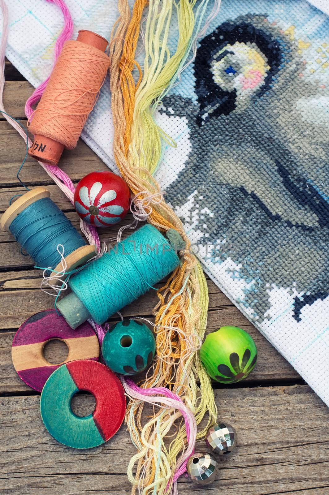 Yarn and thread for embroidering on cloth by hand on wooden surface.Tinted