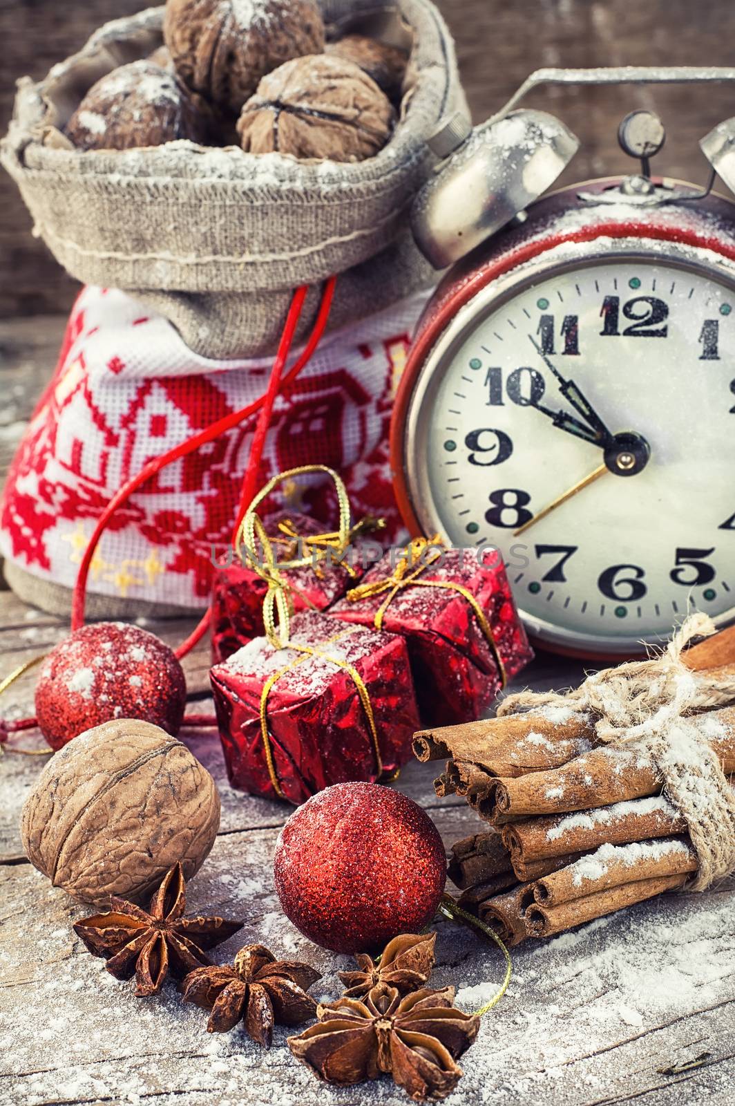 An alarm clock and bag of nuts on the background of Christmas decorations