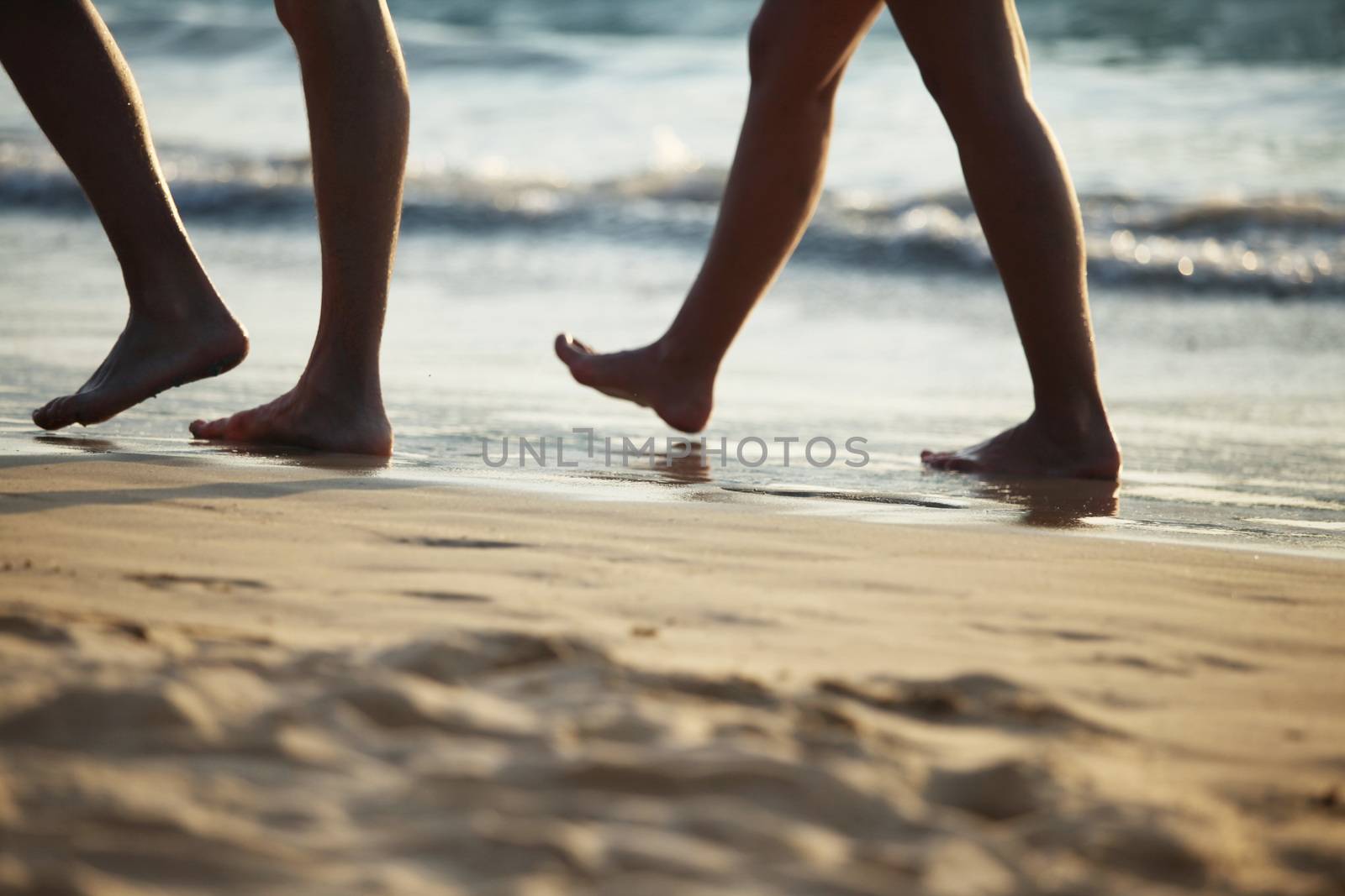 Close-up of people legs walking on beach