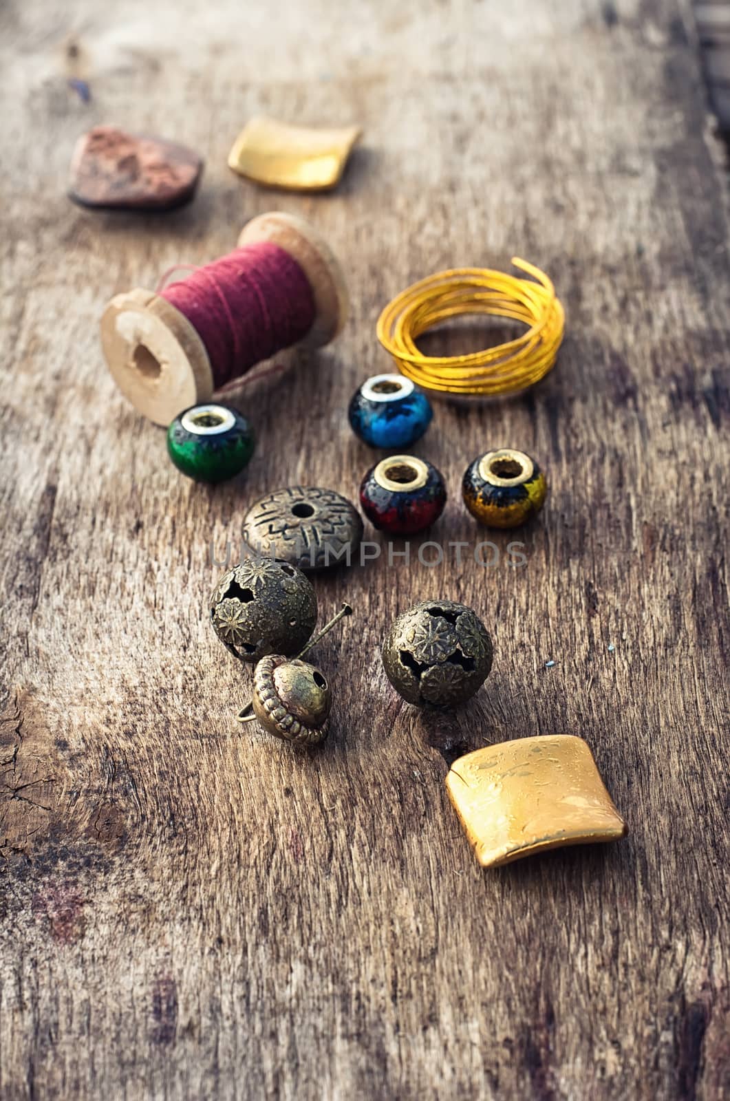 Beads,thread,wire and tools for needlework on the old wooden background